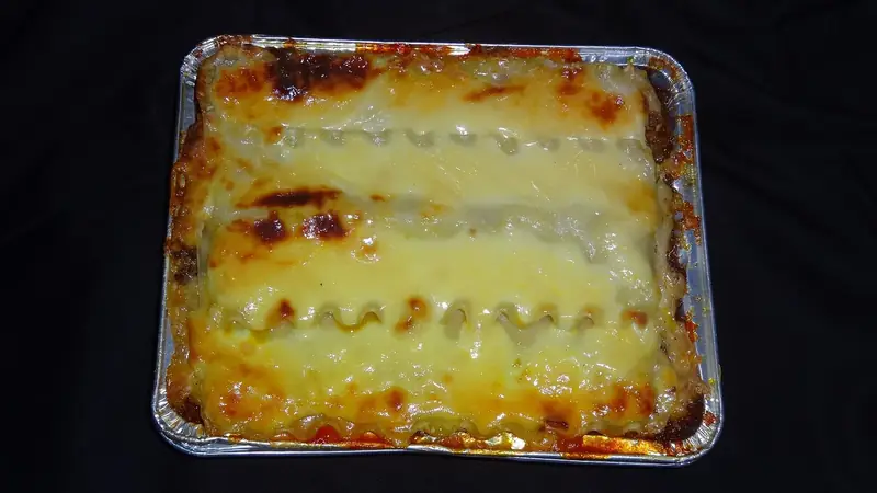 Baked lasagna with browned cheese in a rectangular foil baking pan