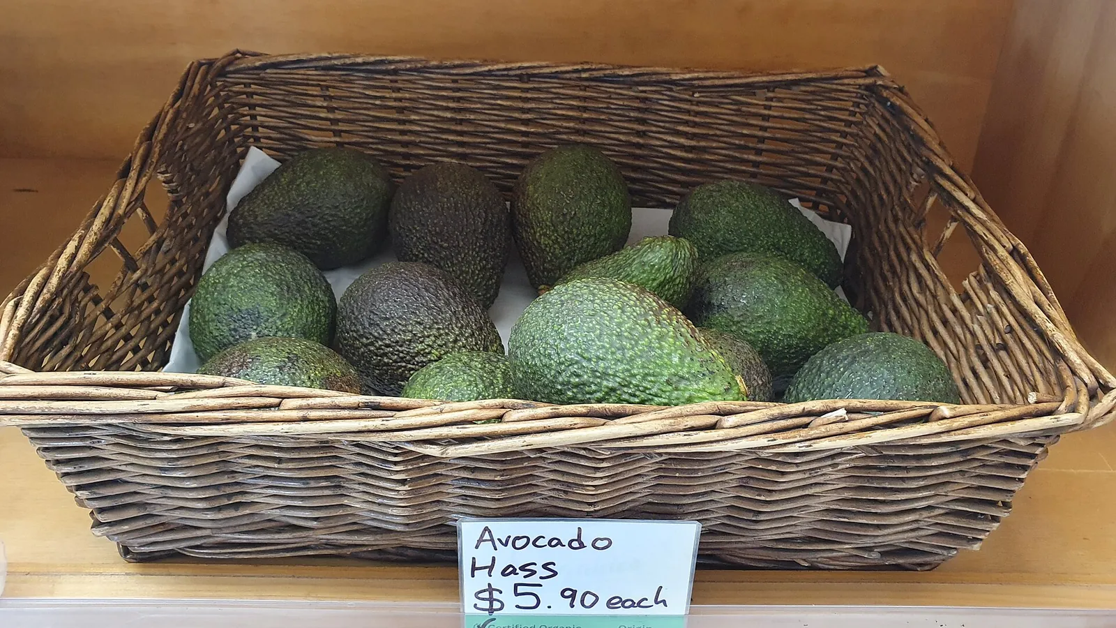 Basket of green and darkening Hass avocados for sale on a store shelf