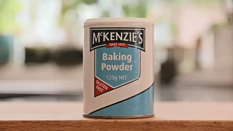 A can of baking powder sitting on a table in a kitchen