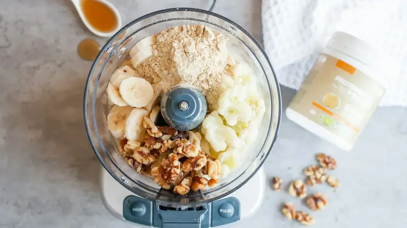 Blender jar filled with frozen fruit and other smoothie ingredients ready to blend