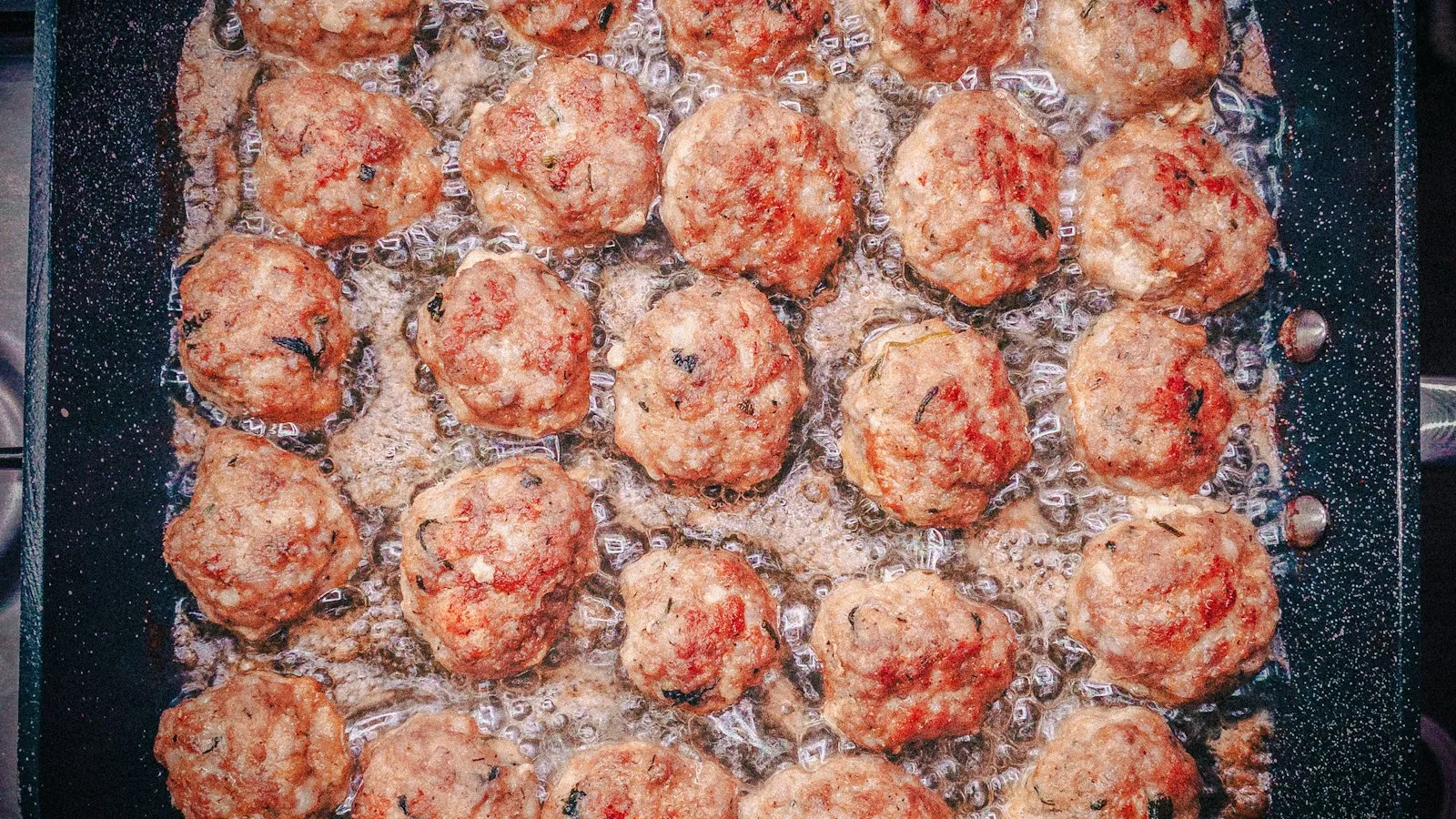Meatballs simmering in tomato sauce in a pan