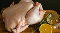 Raw chicken pieces on a brown wooden chopping board