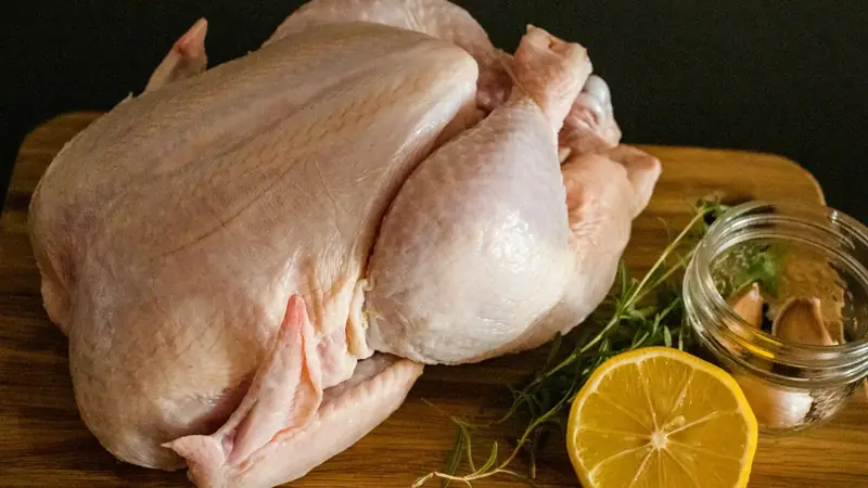 Raw chicken pieces on a brown wooden chopping board