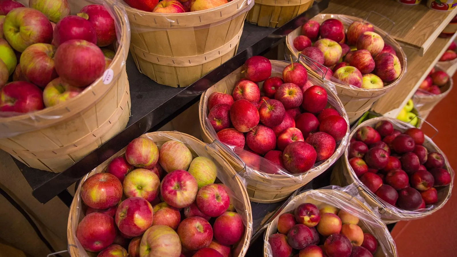 Wooden baskets of red, green and yellow apples of several varieties at a fruit market