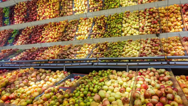 Rows of red, green and yellow apple varieties stacked in a grocery store produce display