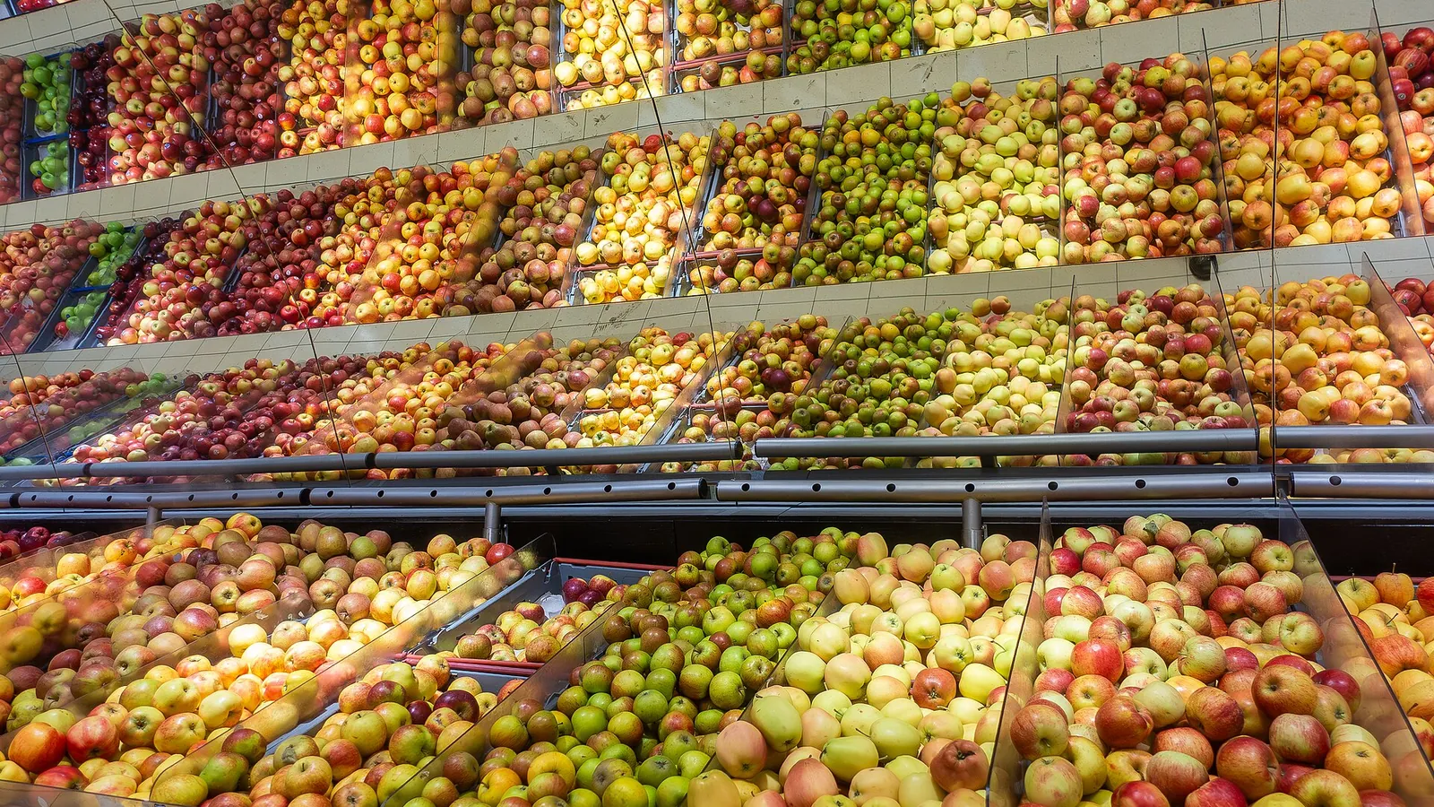 Rows of red, green and yellow apple varieties stacked in a grocery store produce display