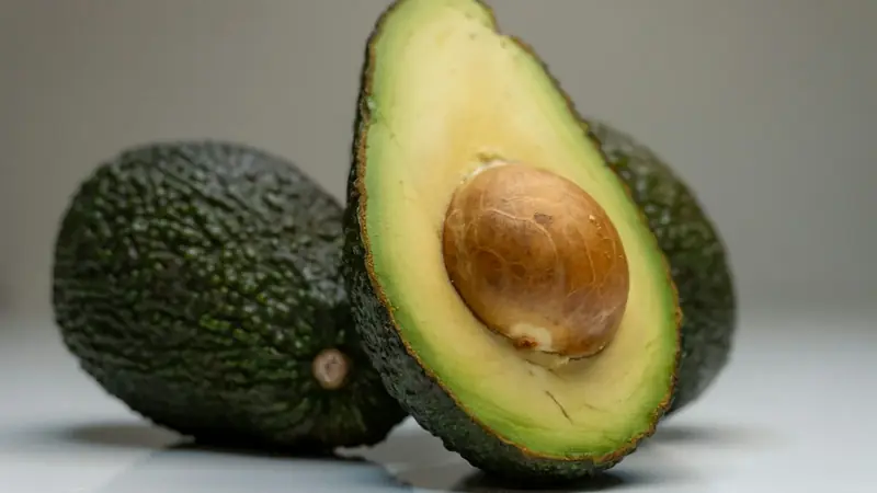 Ripe avocado cut in half on a table, showing green flesh and the pit