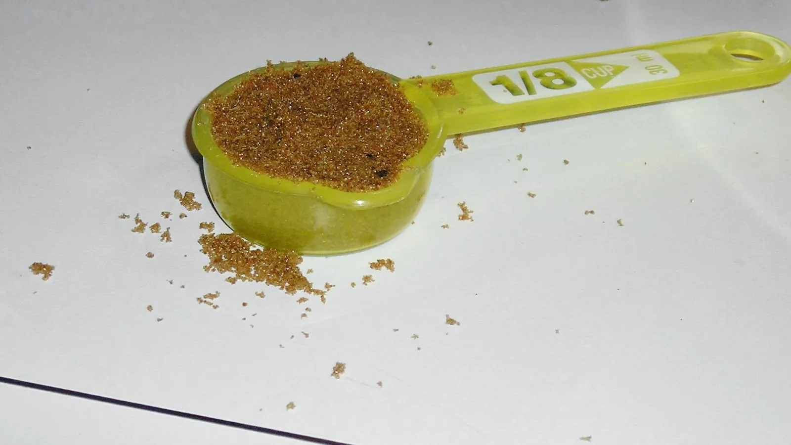 A 1/8 cup measure with a pouring spout filled with brown sugar