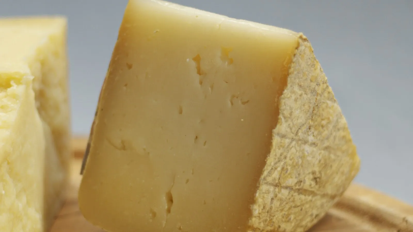 A wedge of aged Pecorino cheese with a natural rind on a dark surface