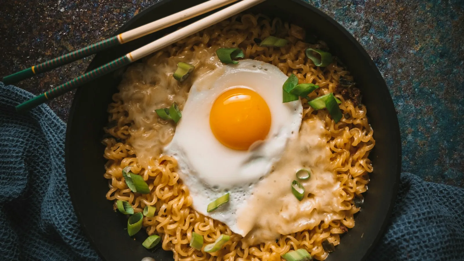 Fried egg sitting over separate grains of rice in a black pan