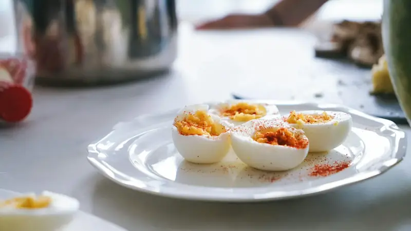 Halved hard boiled eggs peeled and showing firm yellow yolks on a plate