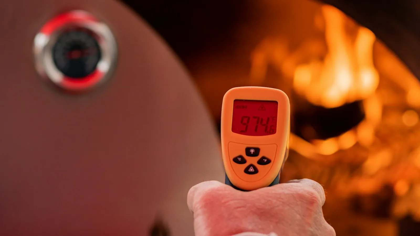 Person holding an instant read thermometer probe near an open fire