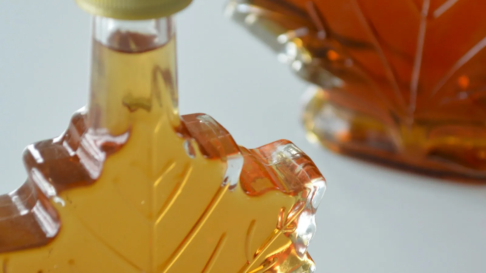 Leaf-shaped glass bottle of maple syrup on a table