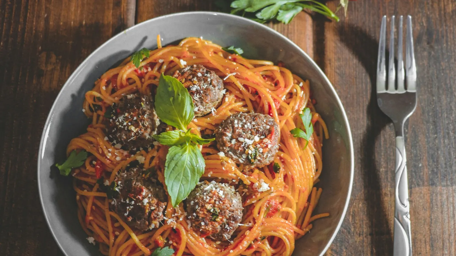 Plate of spaghetti topped with meatballs, tomato sauce and cherry tomatoes