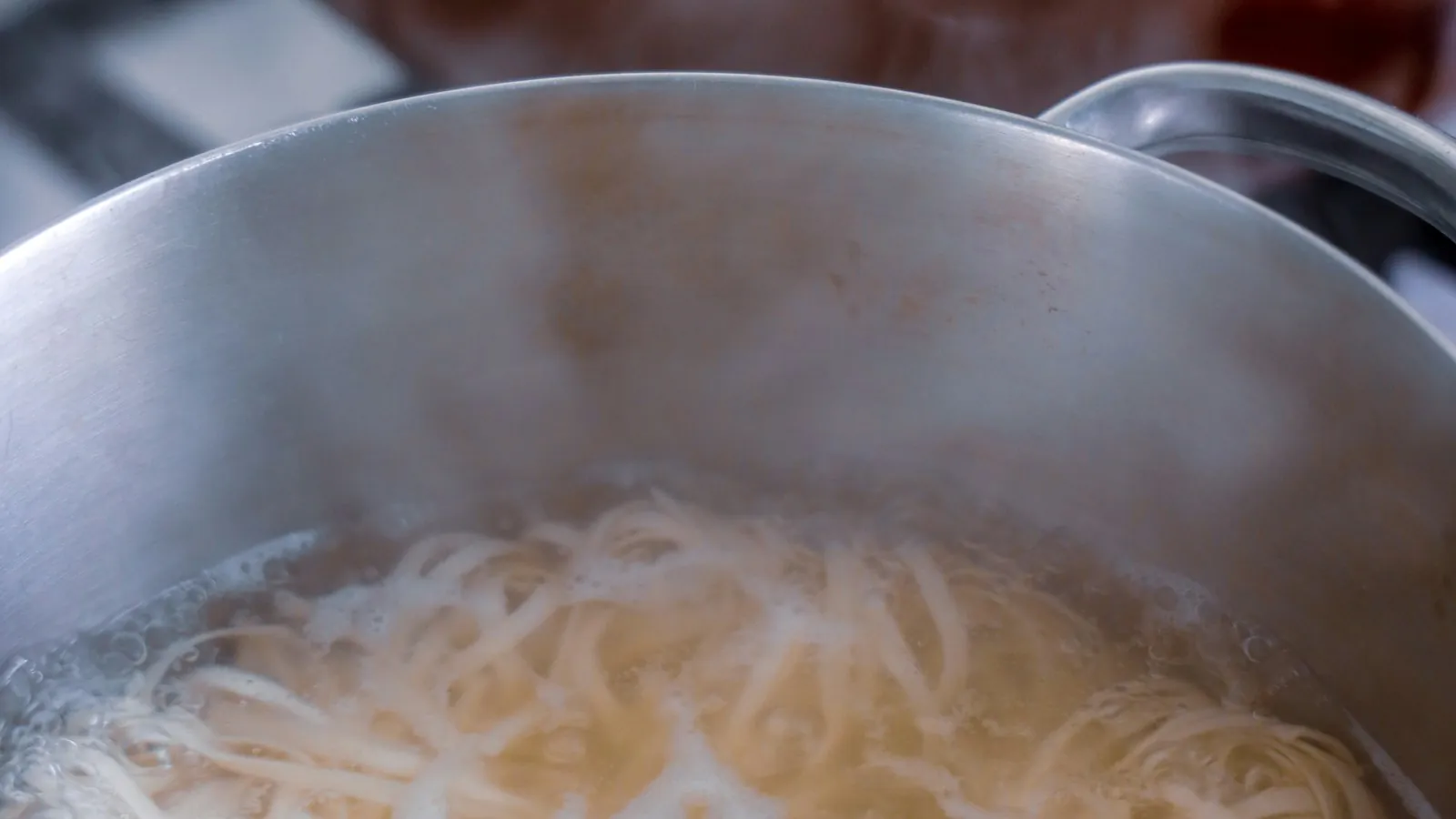 Pale cooked noodles piled in a stainless steel bowl