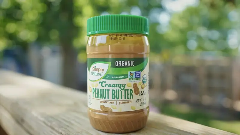 An open jar of creamy peanut butter sitting on a wooden table