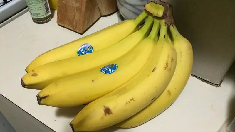 Bunch of yellow bananas with a few small brown marks resting on a kitchen counter
