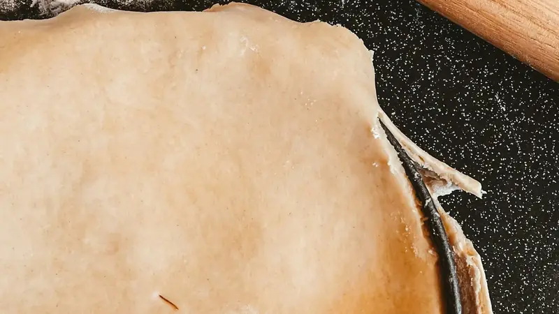 Wooden rolling pin resting on a lightly floured wooden table