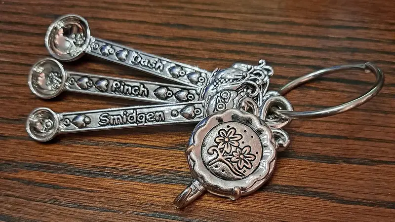 Three tiny pinch dash smidgen measuring spoons on a key ring resting on a wooden table