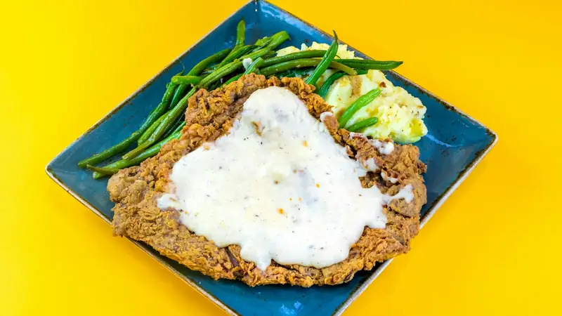 Seared pork chop on a plate with mashed potatoes and brown gravy