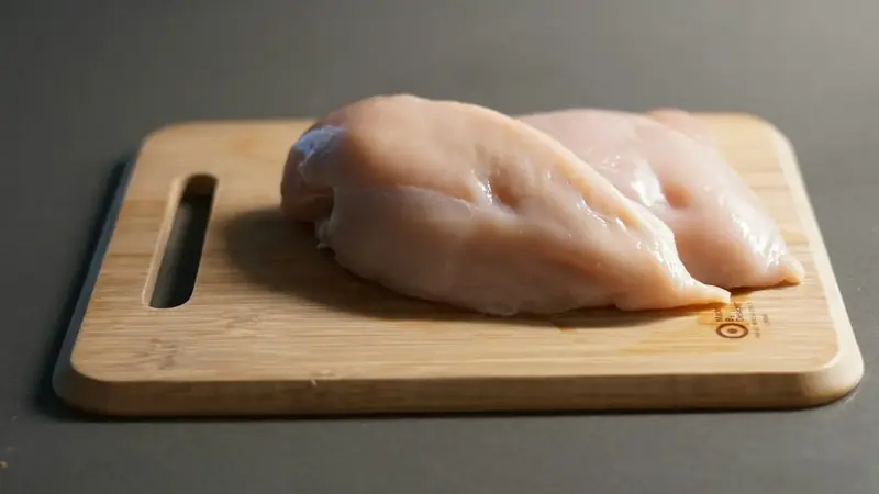 Piece of raw chicken resting on a cutting board