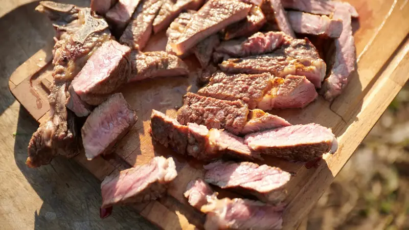 Sliced medium rare steak fanned out on a wooden cutting board