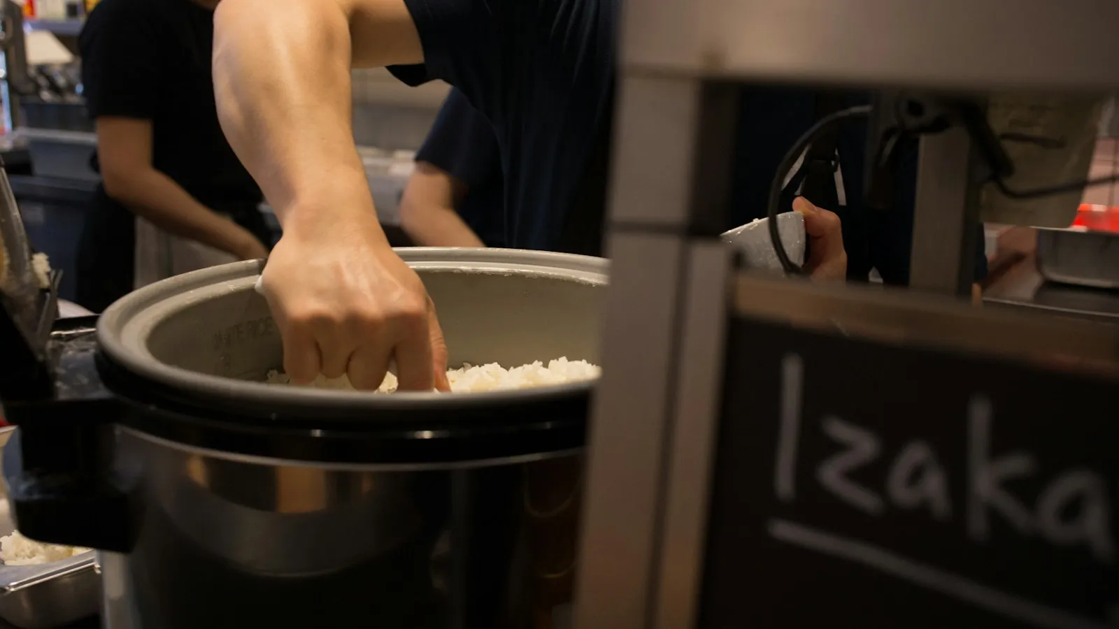 Cook putting rice into a large pot in a restaurant kitchen