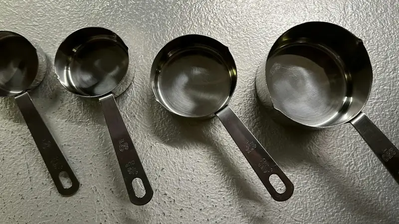 Measuring cup and measuring spoon on a kitchen counter, ready for tablespoons in a cup math