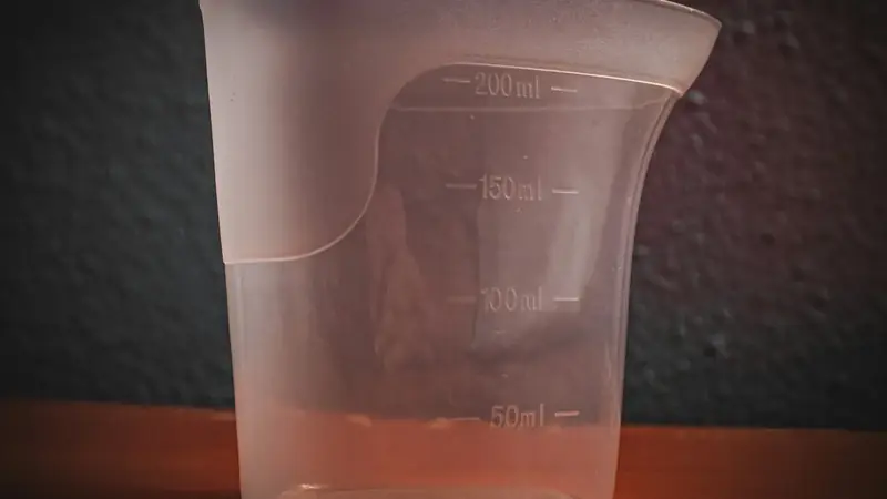 Plastic measuring cup with printed markings on a wooden table