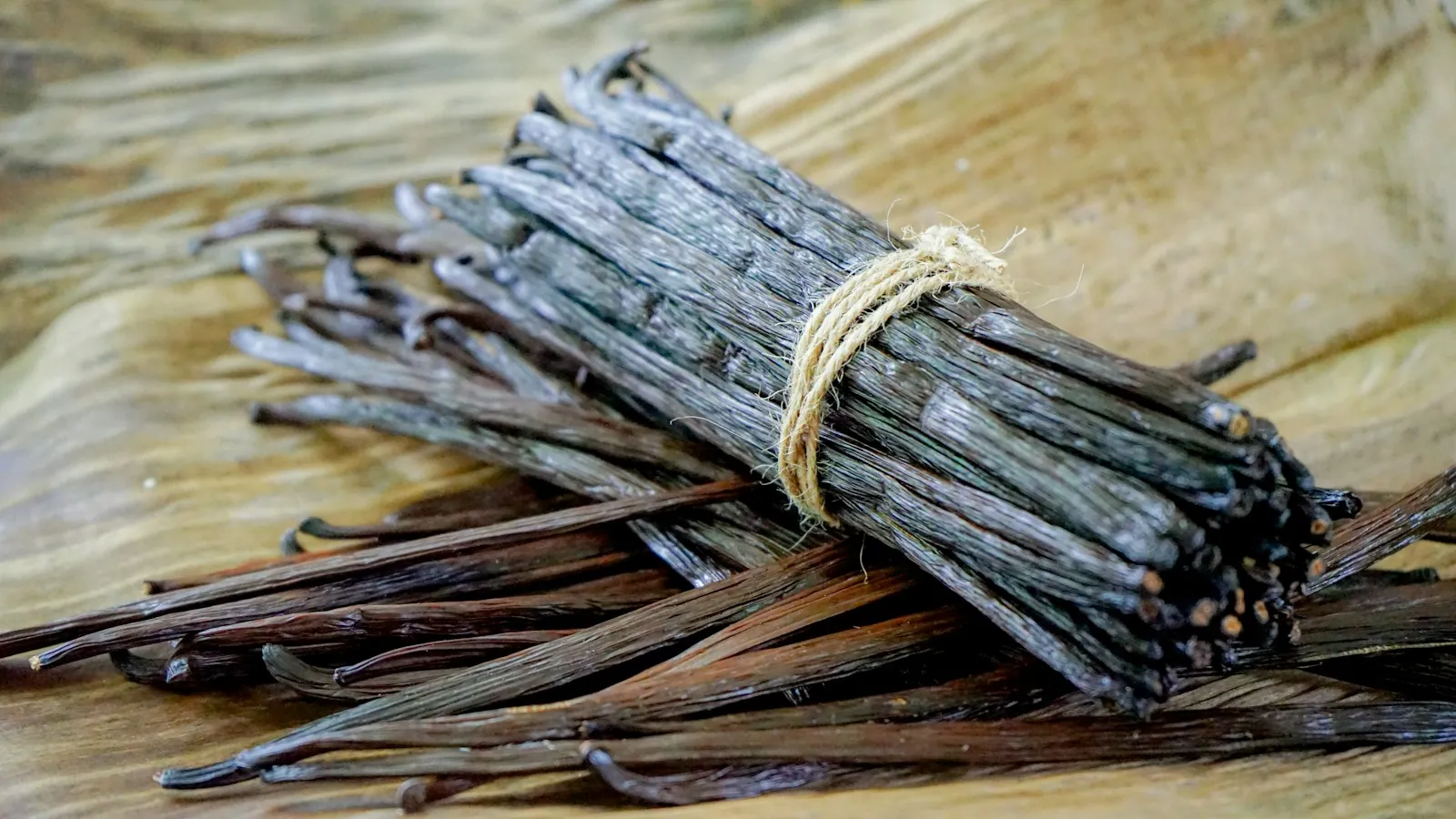 Bundle of dried vanilla beans resting on a wooden table
