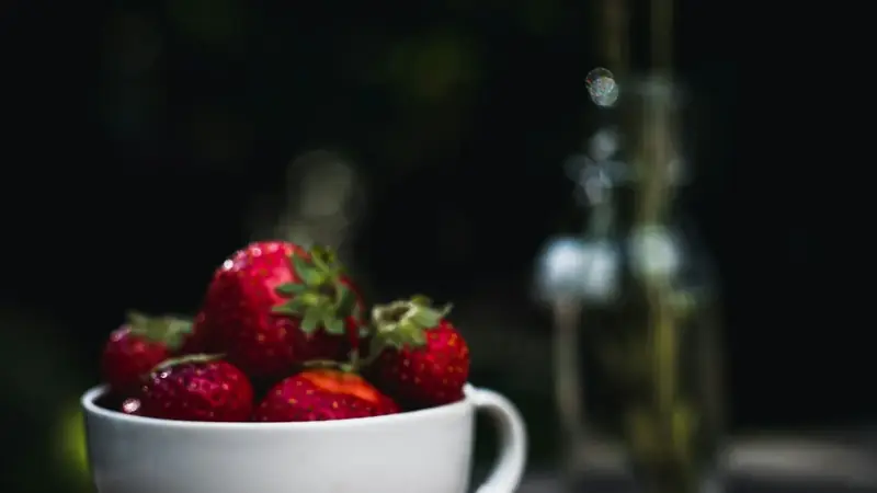 Bowl of fresh strawberries and blueberries sitting on a table