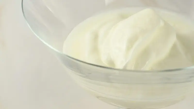 Glass bowl of softly whipped cream on a table